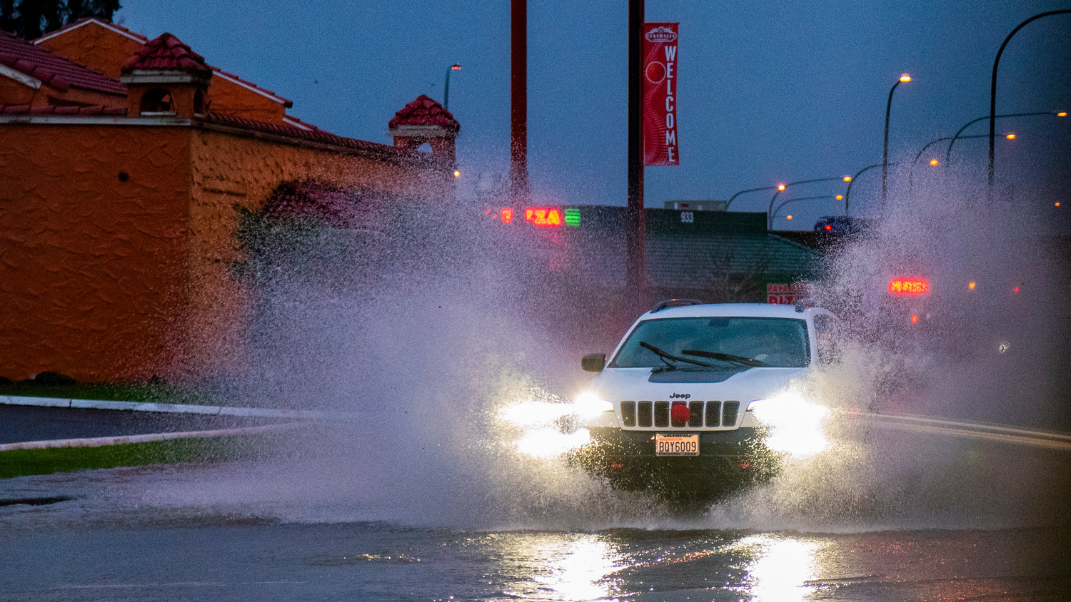Water splashes as a Jeep drives through floodwaters along Harrison Avenue in Centralia on Friday.