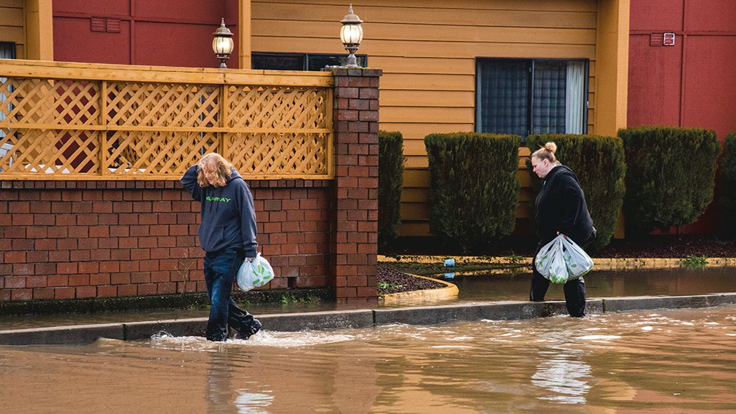 Bags full of items are carried through floodwaters along Harrison Avenue in Centralia on Friday.