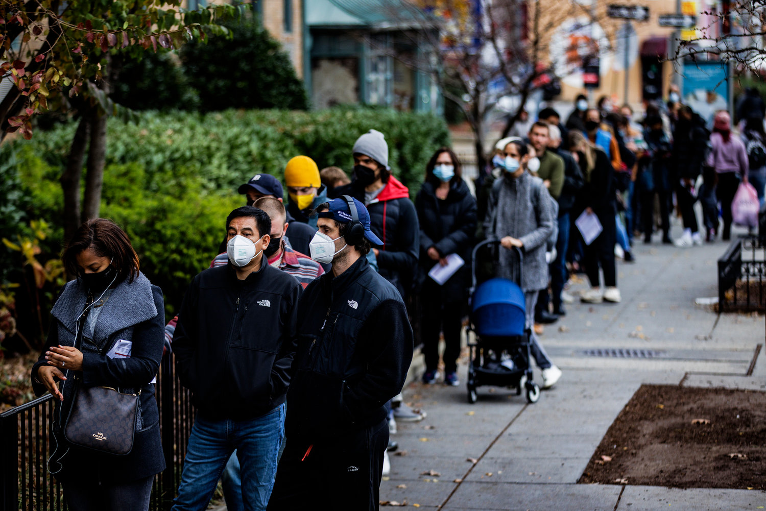 People line up outside of a free COVID-19 just-opened vaccination site in the Hubbard Place apartment building on Friday, Dec. 3, 2021, in Washington, D.C. Experts are hoping the pandemic, with its omicron outbreak, will fade and become endemic in 2022.(Samuel Corum/Getty Images/TNS)