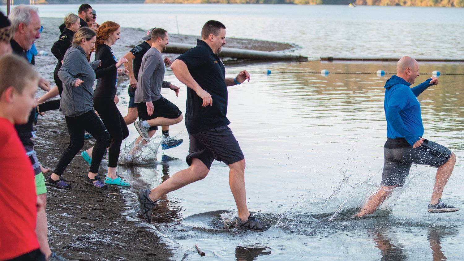 State Rep. Peter Abbarno leads a Polar Plunge into Mayfield Lake followed by Centralia Police Chief Stacy Denham during an event that benefits Lewis County Special Olympics athletes in January 2023.