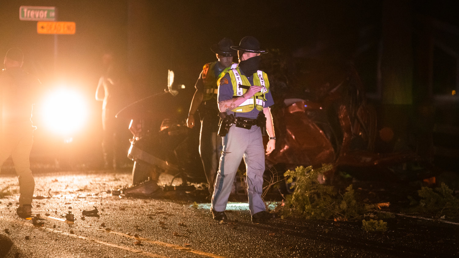 State Patrol walks around a vehicle covered in tree limbs following a crash along Jackson Highway in Chehalis.