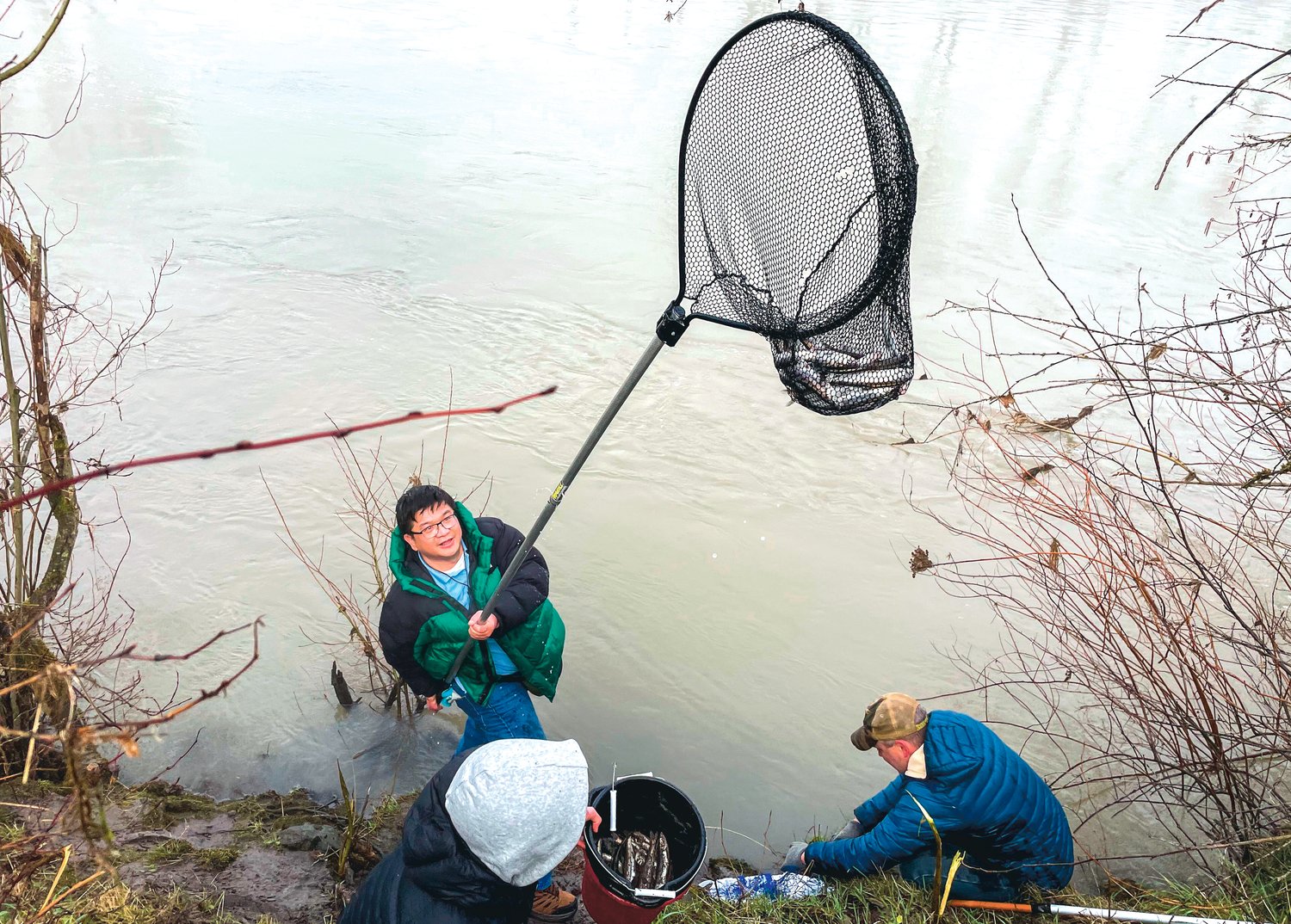 Danh Nguyen smiles while holding a net full of smelt on the bank of the Cowlitz River Saturday morning in Castle Rock.