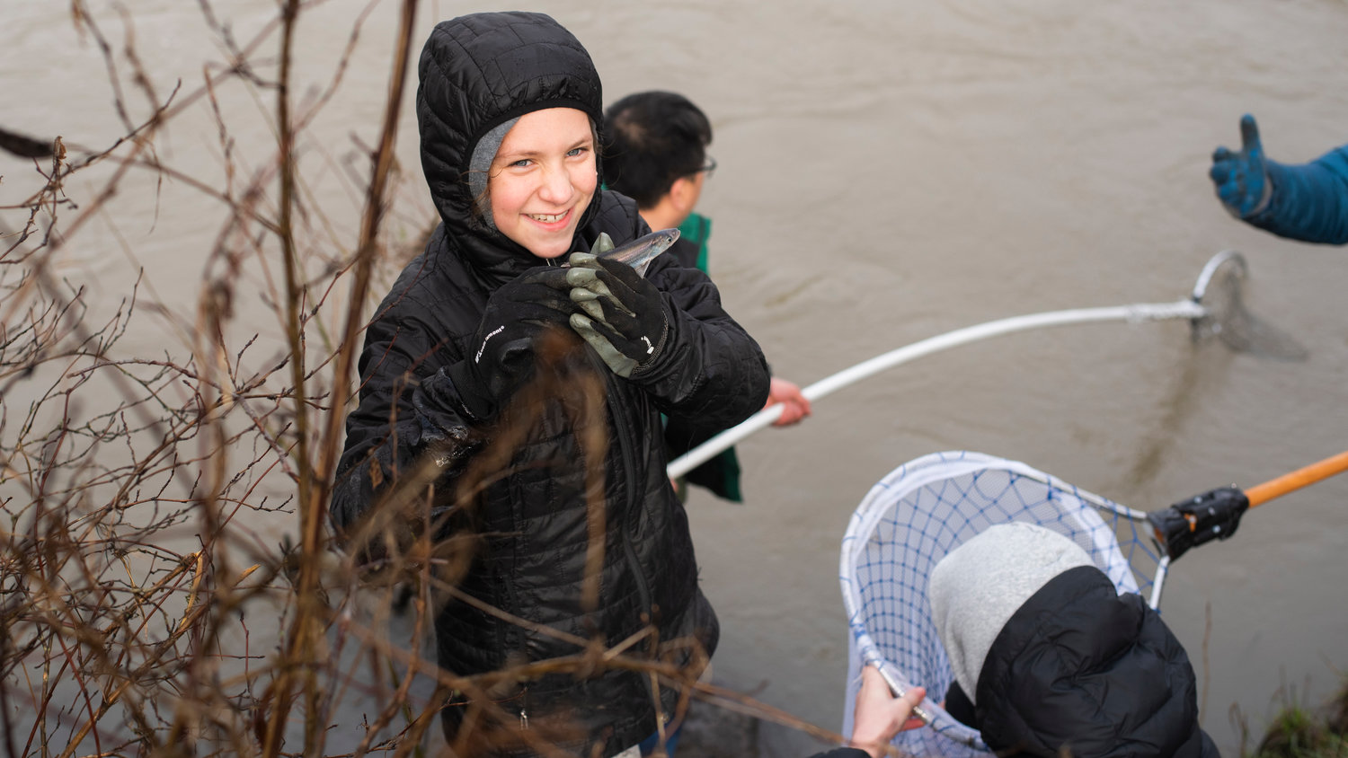 Mirabel Burger, 10, smiles and holds up a smelt scooped up from the Cowlitz River by net alongside family members and other anglers in Castle Rock in 2022.