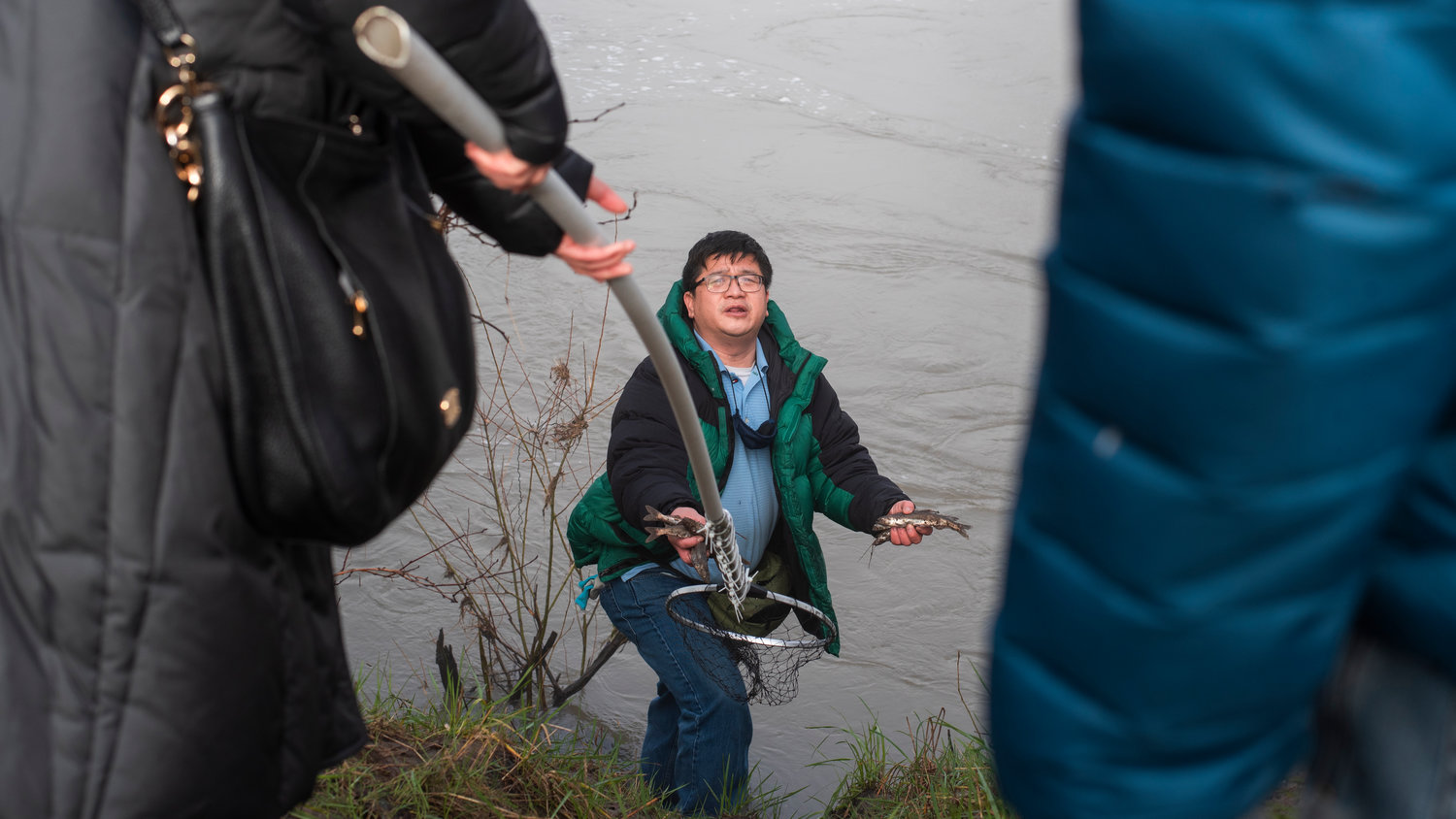 Danh Nguyen holds handfuls of smelt on the bank of the Cowlitz River in Castle Rock in 2022.