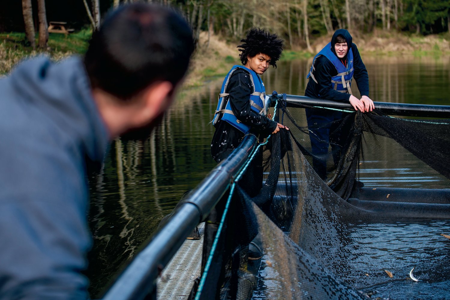 Onalaska High School aquaculture students hold onto netting as fish are sucked out of Carlisle Lake Friday morning and transferred into Gheer Creek.