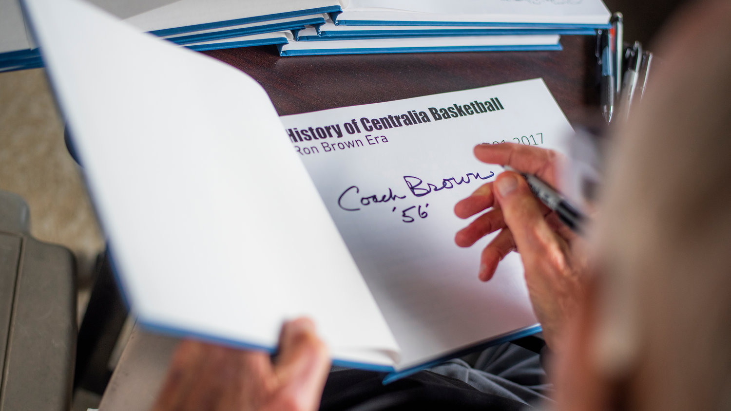 Coach Ron Brown signs a copy of a book titled the History of Centralia Basketball which details the Ron Brown Era. Procedes from book sales will benefit the Centralia Boys Basketball Program. On top of printing costs, $5,000 has already been raised for the program.