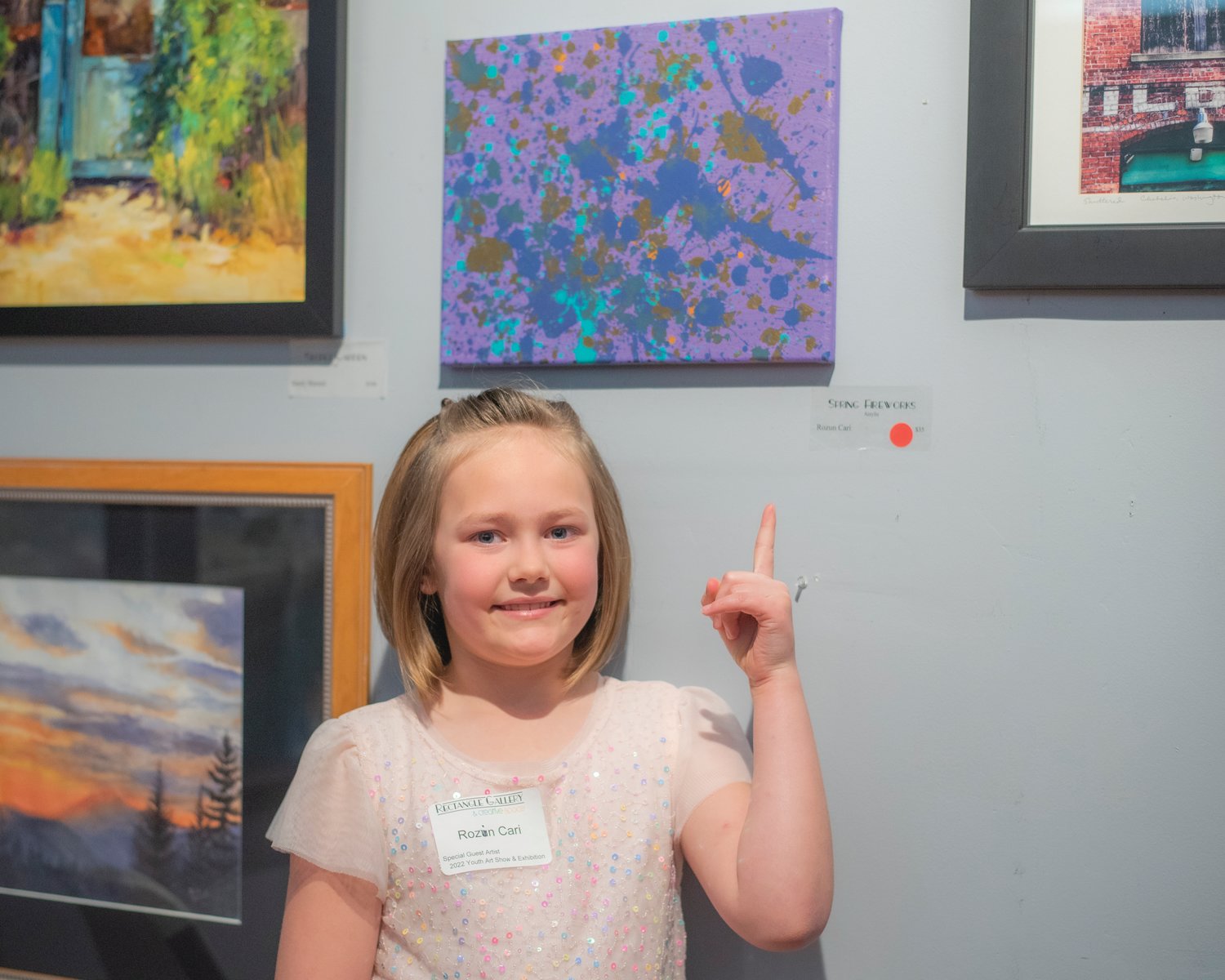 Rozlin Cari, 7, a student at the St. Joseph Catholic School, smiles and points to her acrylic creation after it sold Friday at the Rectangle Gallery & Creative Space in Centralia.