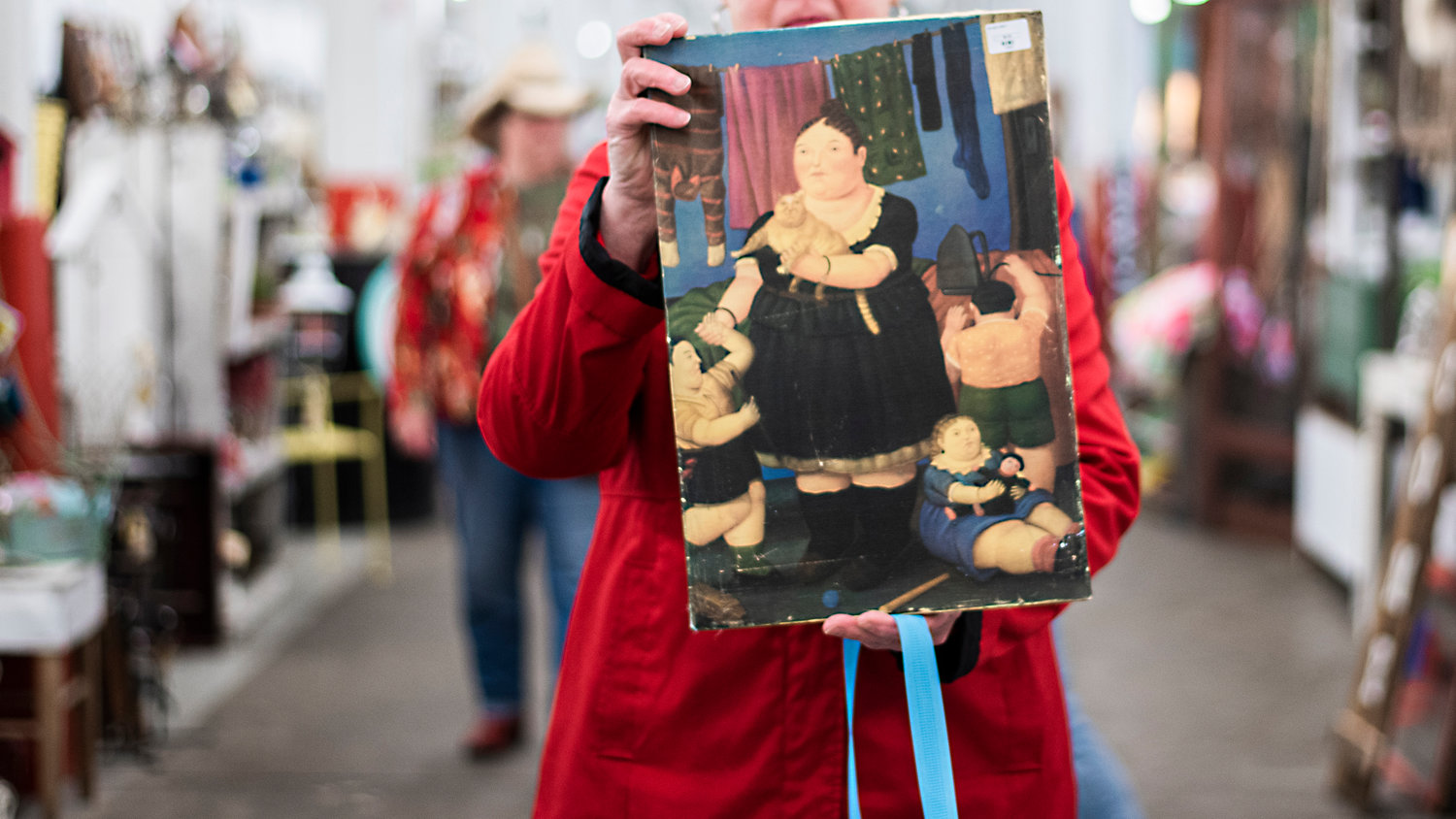 Diane Satterlee, of Centralia, sports the red coat she wears every year to the Country Chicks Spring Show holding up a piece of art she purchased Friday morning.