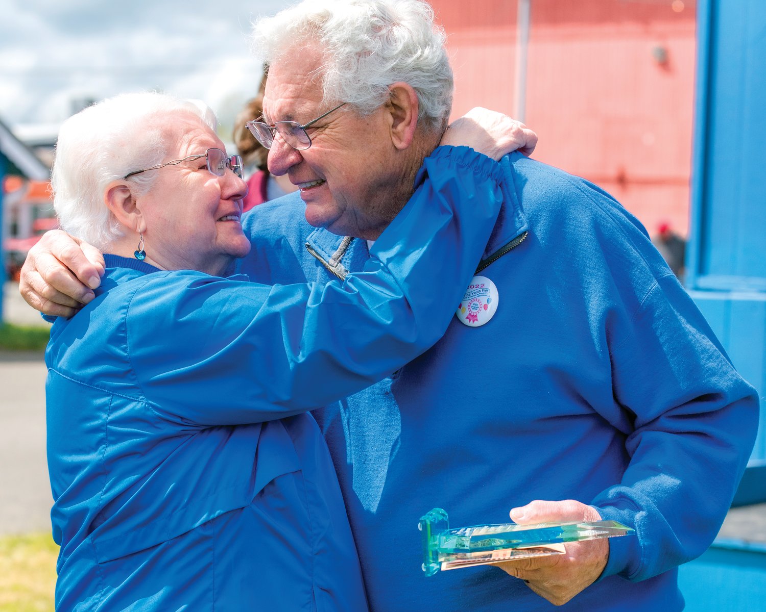 Lee Coumbs smiles and hugs his wife, Bonnie, after receiving a surprise award for 40 years of service Sunday during the Spring Youth Fair in Centralia.