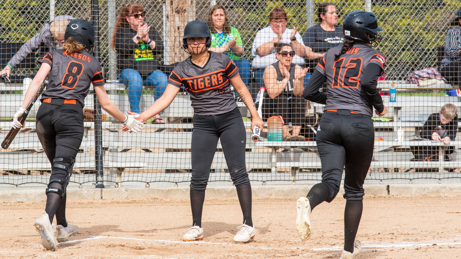Centralia’s Lauren Wasson (8) and Makayla Chavez (10) high-five as Jimena Luis (12) runs toward the dugout during a game against W.F. West on Wednesday.