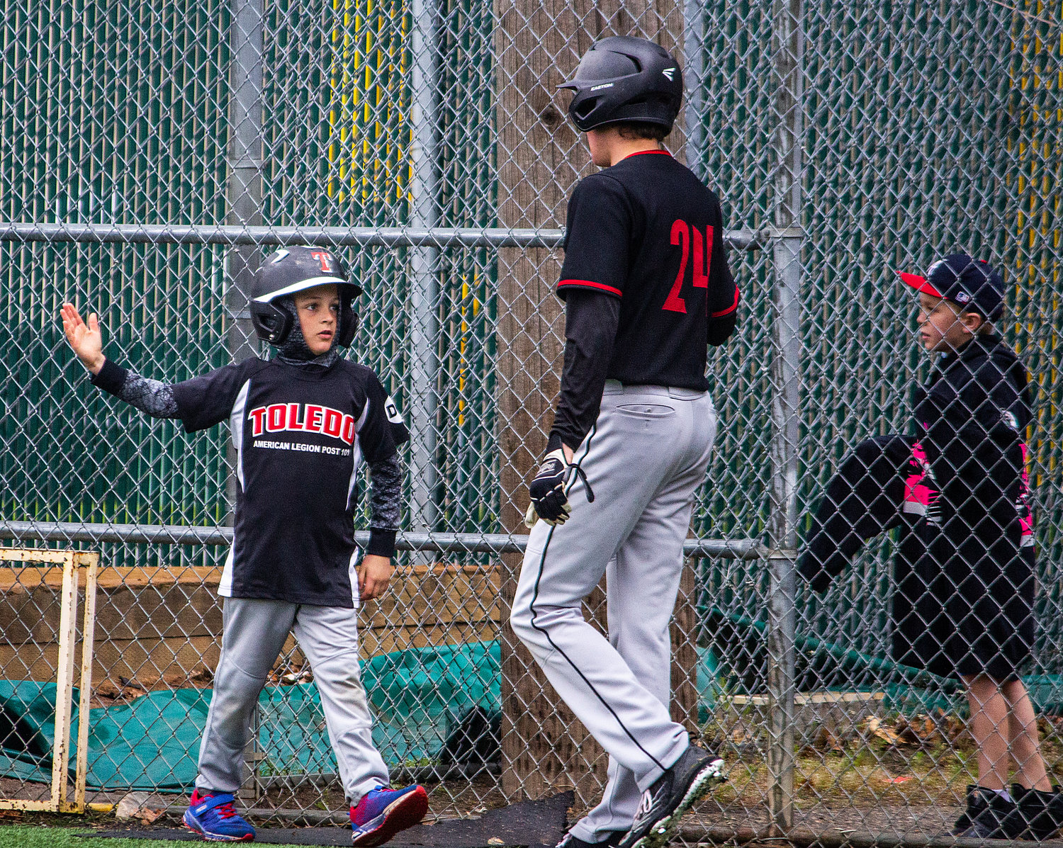 Toledo's ball boy high-fives Kaven Winters during a 2B regional round game against Chewelah at Shadle Park May 21.