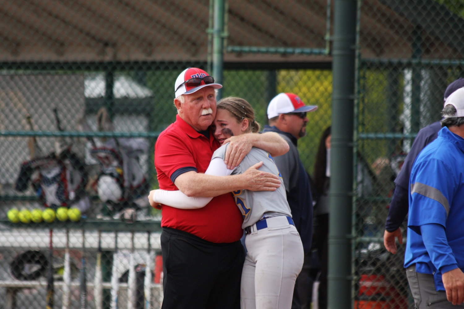 Pe Ell-Willapa Valley fastpitch coach Ken Olson comforts his granddaughter Danika Hallom, who plays centerfield for Adna, after PWV defeated Adna for the title. Olson recently announced this would be his final season after a long and successful coaching career.