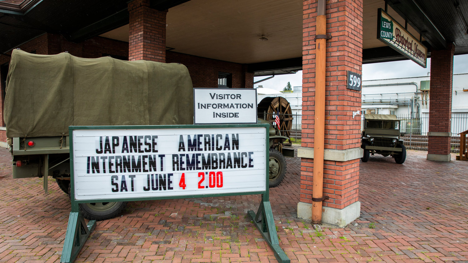 Signs are displayed next to vintage military vehicles at the Lewis County Historical Museum in Chehalis during a Japanese American internment remembrance.