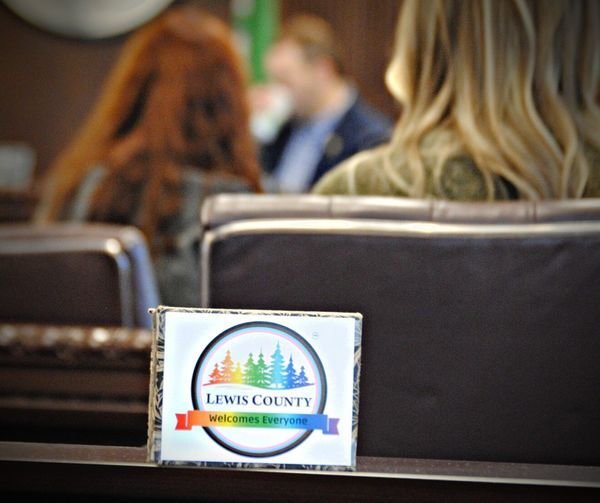An altered version of the Lewis County logo reads “Lewis County Welcomes Everyone” during a meeting.