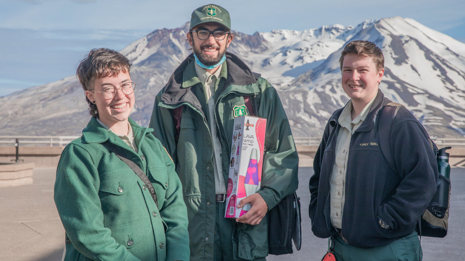 From left, Madisyn Emley, Nishan Mahdasian, and Skye Clark, Park Rangers at the Johnston Ridge Observatory smile for a photo in front of Mount St. Helens on Wednesday.