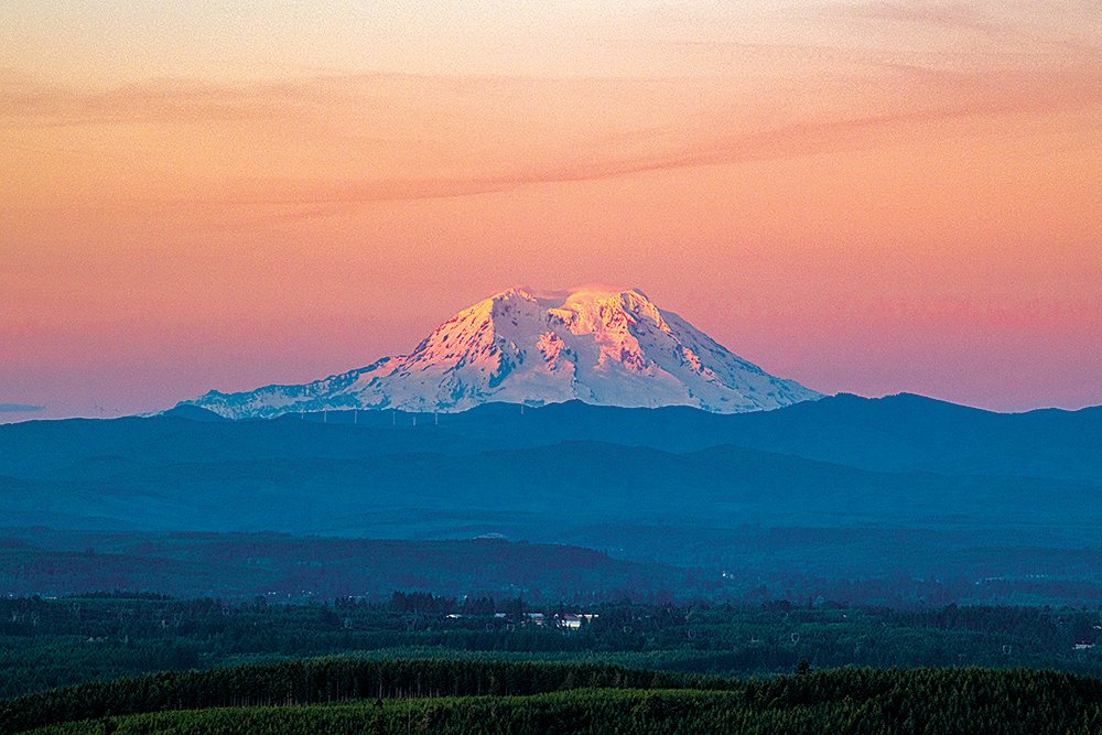 Mount Rainier is cast in a hazy pink during the sunset, pictured from Crego Hill in Adna on the summer solstice.