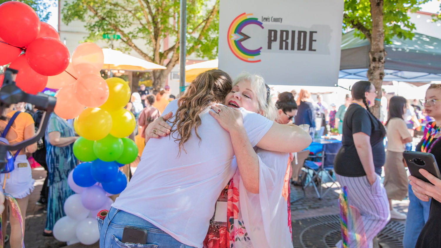 Hope Schumacher receives an embrace after cutting a ribbon to mark the beginning of a pride event in downtown Centralia after honoring the life of Rikkey Outumuro.
