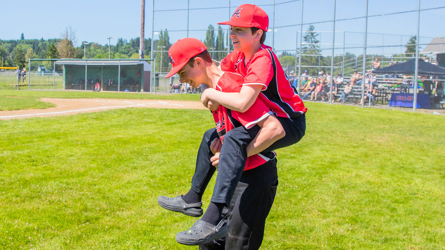Dane Akin rides on the back of Colton Weiss as athletes walk onto the field at Stan Hedwall Park in Chehalis on Saturday.