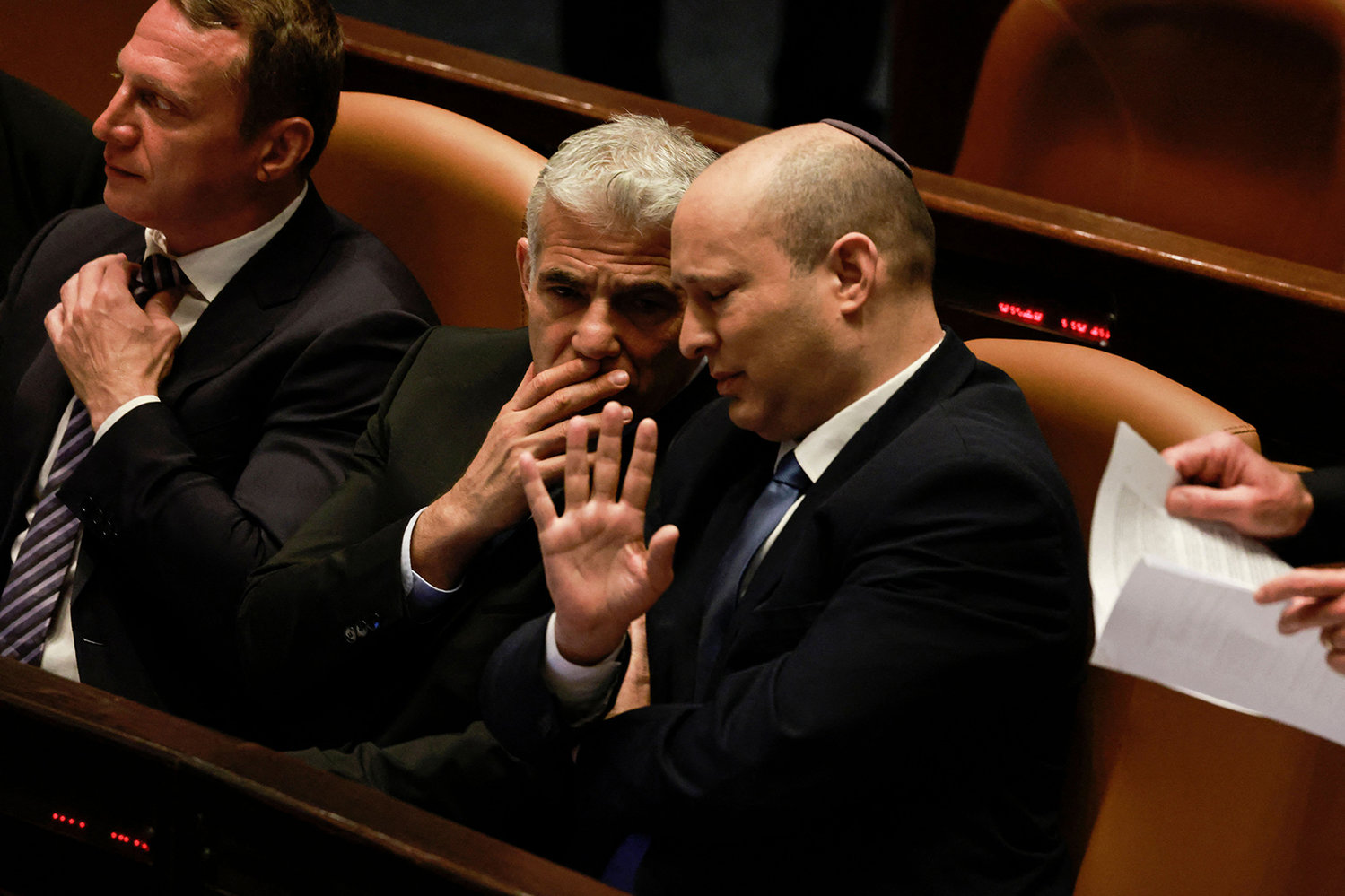 Israeli Minister of Foreign Affairs Yair Lapid (left) and outgoing Prime Minister Naftali Bennett, speak to each other at the Knesset (parliament), following the dissolution of the parliament, in Jerusalem on June 30, 2022. - Israeli lawmakers dissolved parliament today, forcing the country's fifth election in less than four years, with Foreign Minister Yair Lapid set to take over as caretaker prime minister at midnight. The final dissolution bill, which passed with 92 votes in favour none against, ends the year-long premiership of Naftali Bennett, who led an eight-party coalition that was backed by an Arab party, a first in Israeli history. (Menahem Kahana/AFP via Getty Images/TNS)
