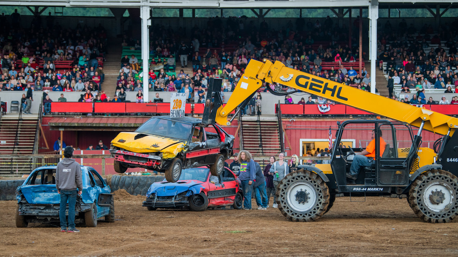 A car is hoisted into the air in front of the Southwest Washington Fairgrounds grandstands Sunday evening following the demolition derby import round.