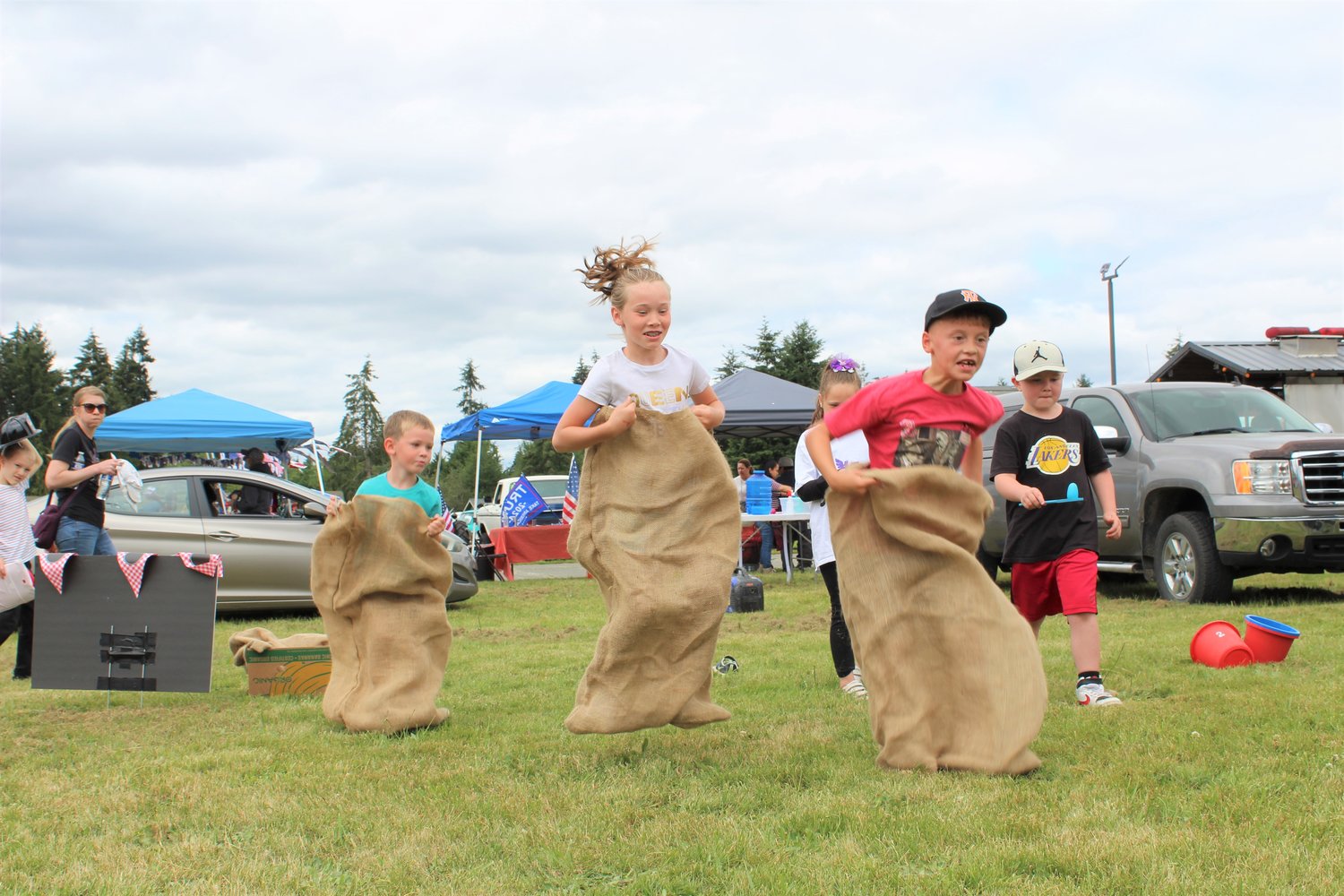 Wyatt Ozretitch, 4, Ashlynn Ozretitch, 9, and Wes Grandorff, 7, race against one another in the potato sack race in the Napavine Funtime Festival kids games area.