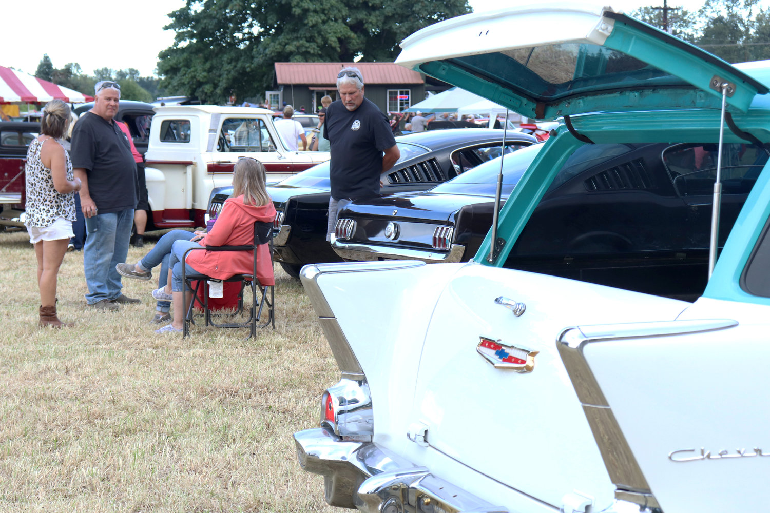 People tailgate beside their vehicles at the Adna Camp & Cruise Car Show in Adna on Friday.
