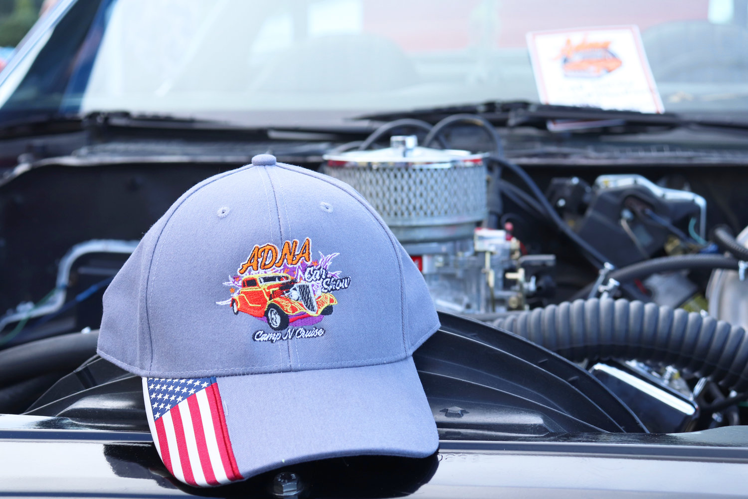 An event cap rests on an engine at the Adna Camp & Cruise Car Show in Adna on Friday.