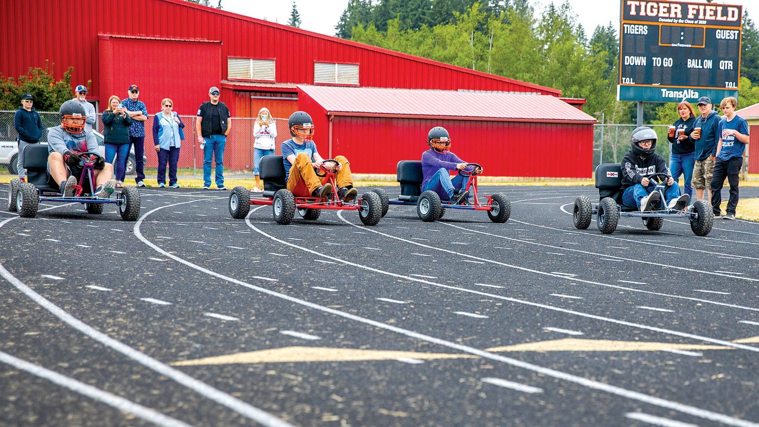 Drivers pilot go-karts and sport helmets as they take off from the start line around the Napavine High School track on Thursday.