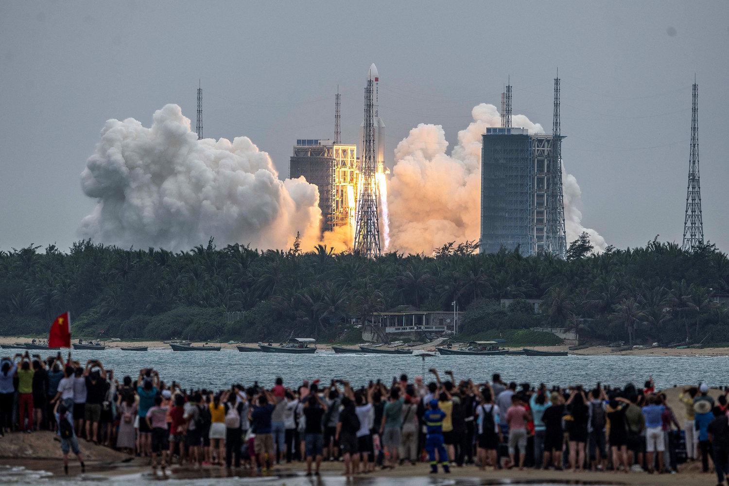 People watch a Long March 5B rocket, carrying China's Tianhe space station core module, as it lifts off from the Wenchang Space Launch Center in southern China's Hainan province on April 29, 2021. (STR/AFP/Getty Images/TNS)