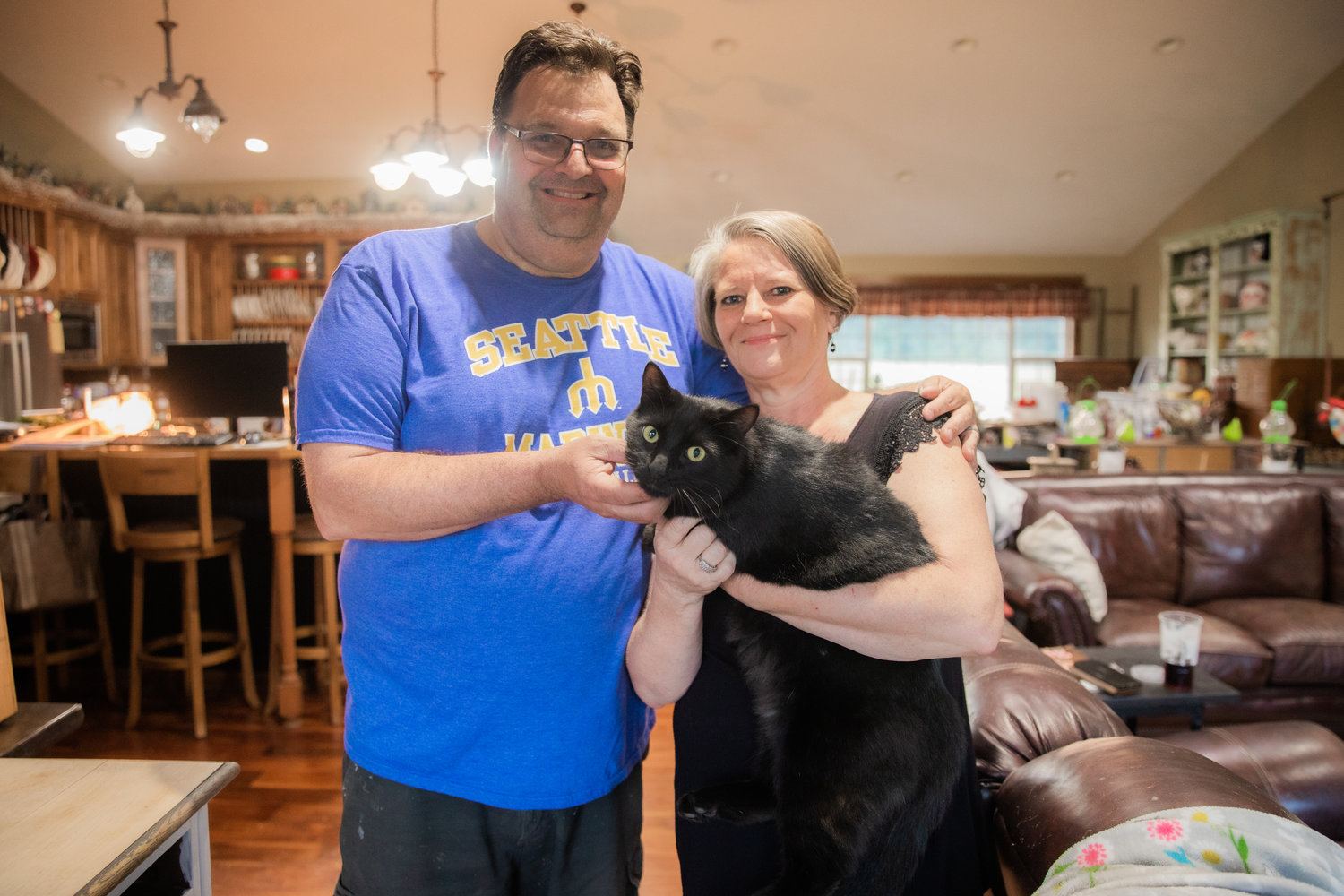 Ken and Julie Wiseman smile for a photo with their cat Raven on Wednesday after he was rescued from a utility pole by Lewis County Public Utility District employees outside their residence along Frogner Road.