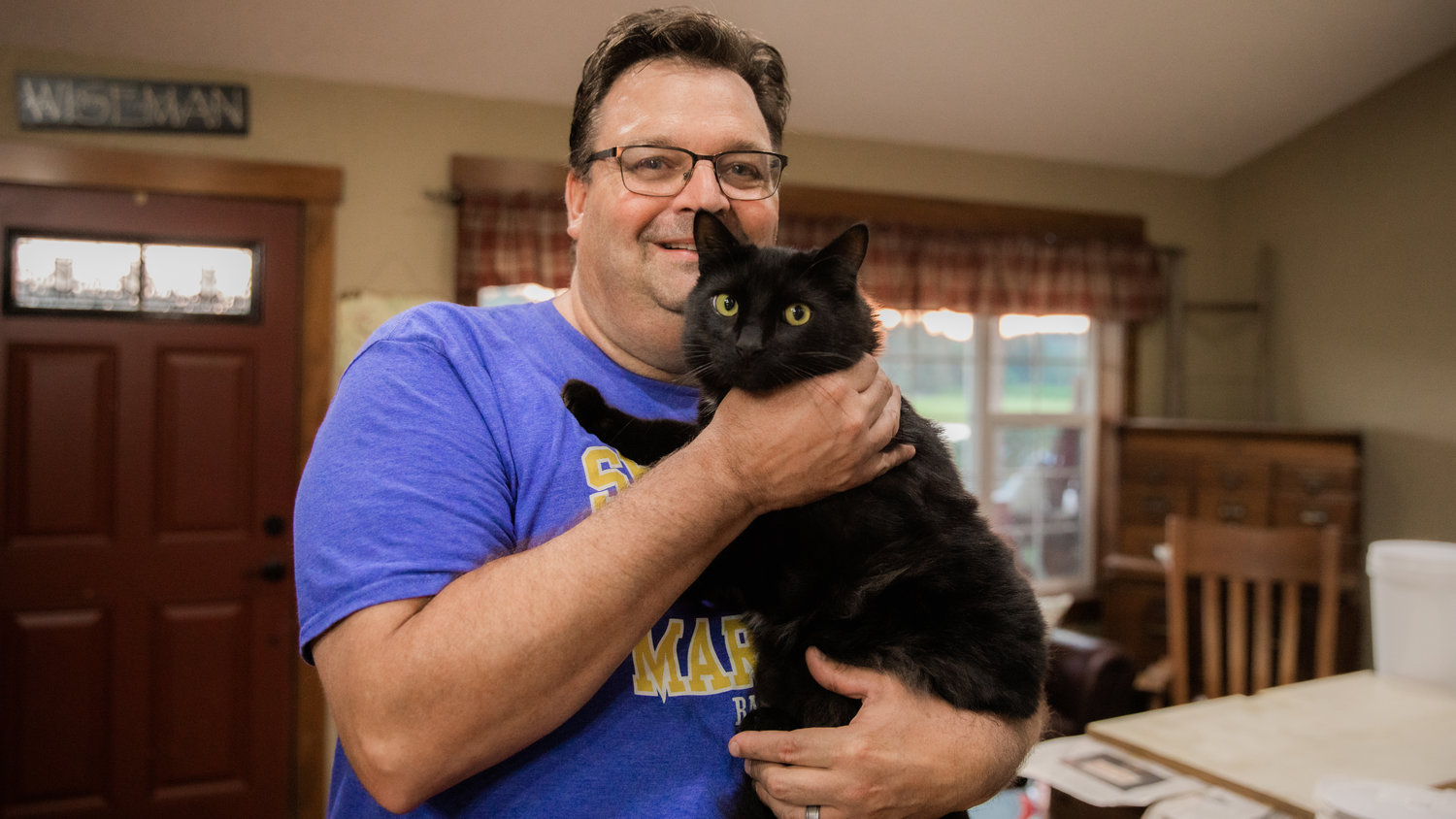 Ken Wiseman smiles for a photo with his cat Raven on Wednesday after he was rescued from a utility pole by Lewis County Public Utility District employees outside his residence along Frogner Road.