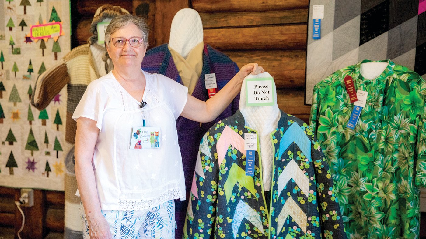 Cindy Lithrope, of Tenino, poses for a photo next to a coat she designed on display during the Thurston County Fair on Thursday.