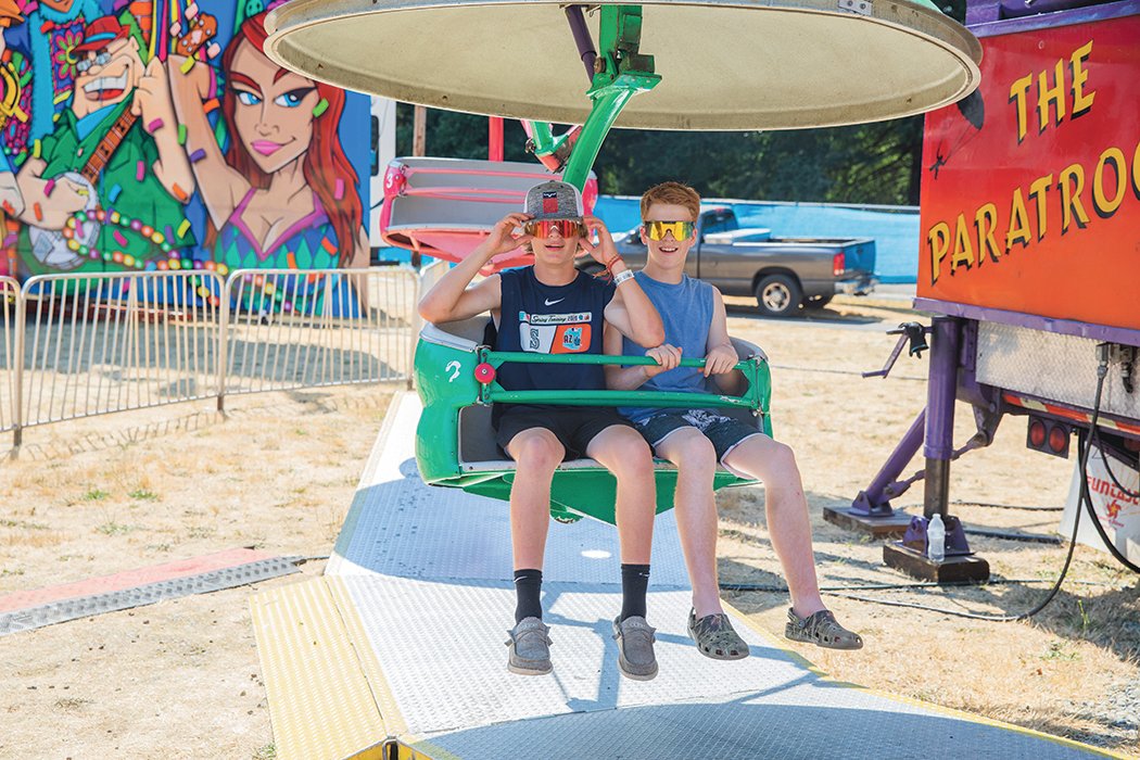 Visitors smile and sport sunglasses while on a ride at the Thurston County Fairgrounds on Thursday.