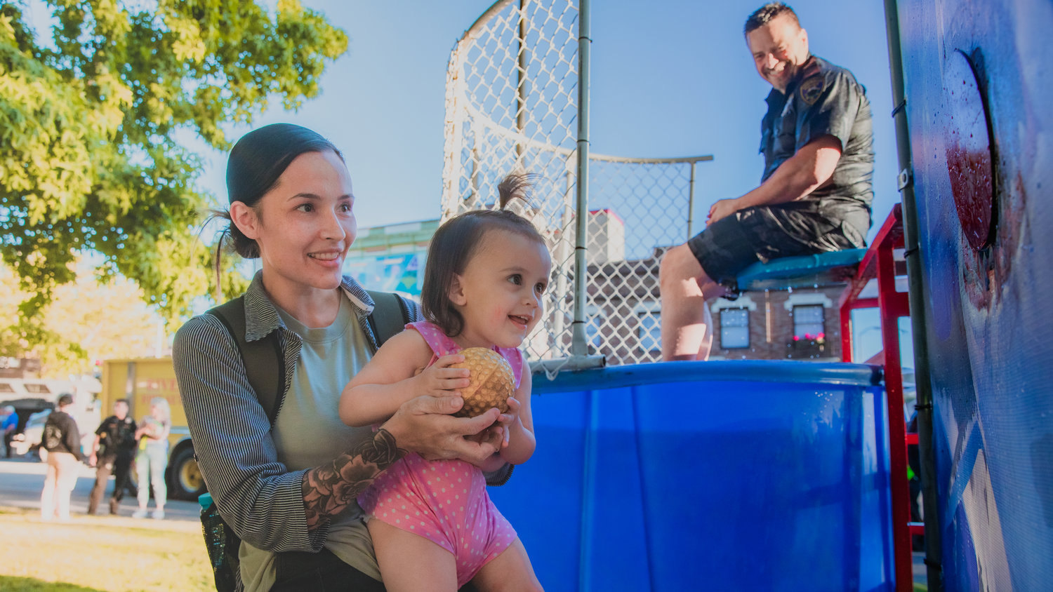 Genesis Gonzalez, 2, prepares to soak Centralia Police Chief Stacy Denham in a dunk tank Tuesday at George Washington Park during a National Night Out event.