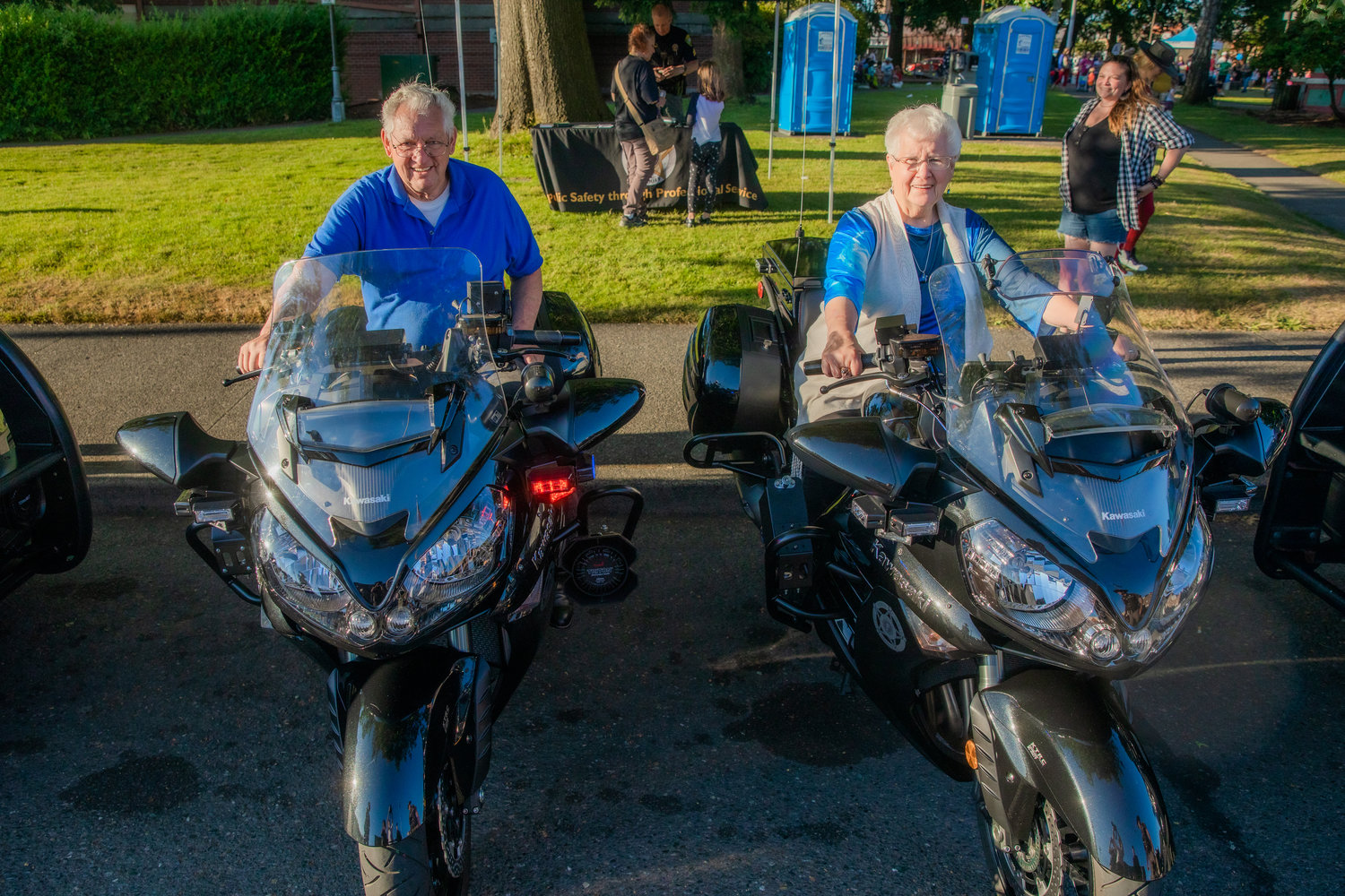 Lee Coumbs and Bonnie Canaday smile for a photo on motorcycles from the Lewis County Sheriff’s Office Tuesday at George Washington Park during a National Night Out event in downtown Centralia.