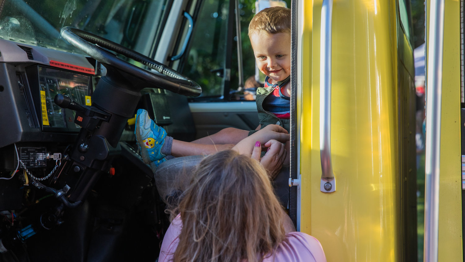 Dawson Thunberg, 2, smiles while sitting in a fire engine Tuesday at George Washington Park during a National Night Out event in downtown Centralia.