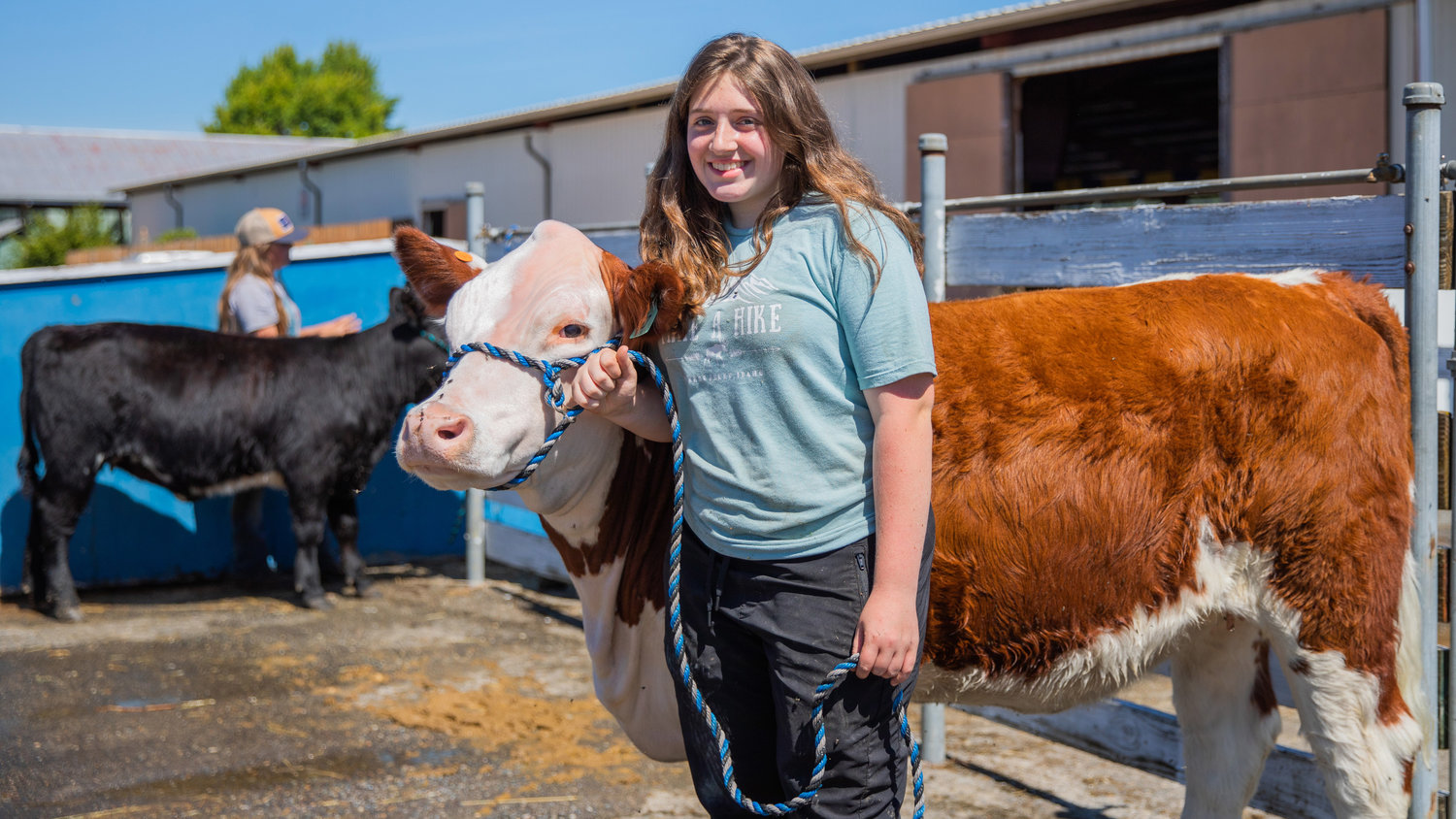 Kaelie Tobias smiles for a photo with her cow Hazel Monday afternoon at the Southwest Washington Fairgrounds in Centralia.
