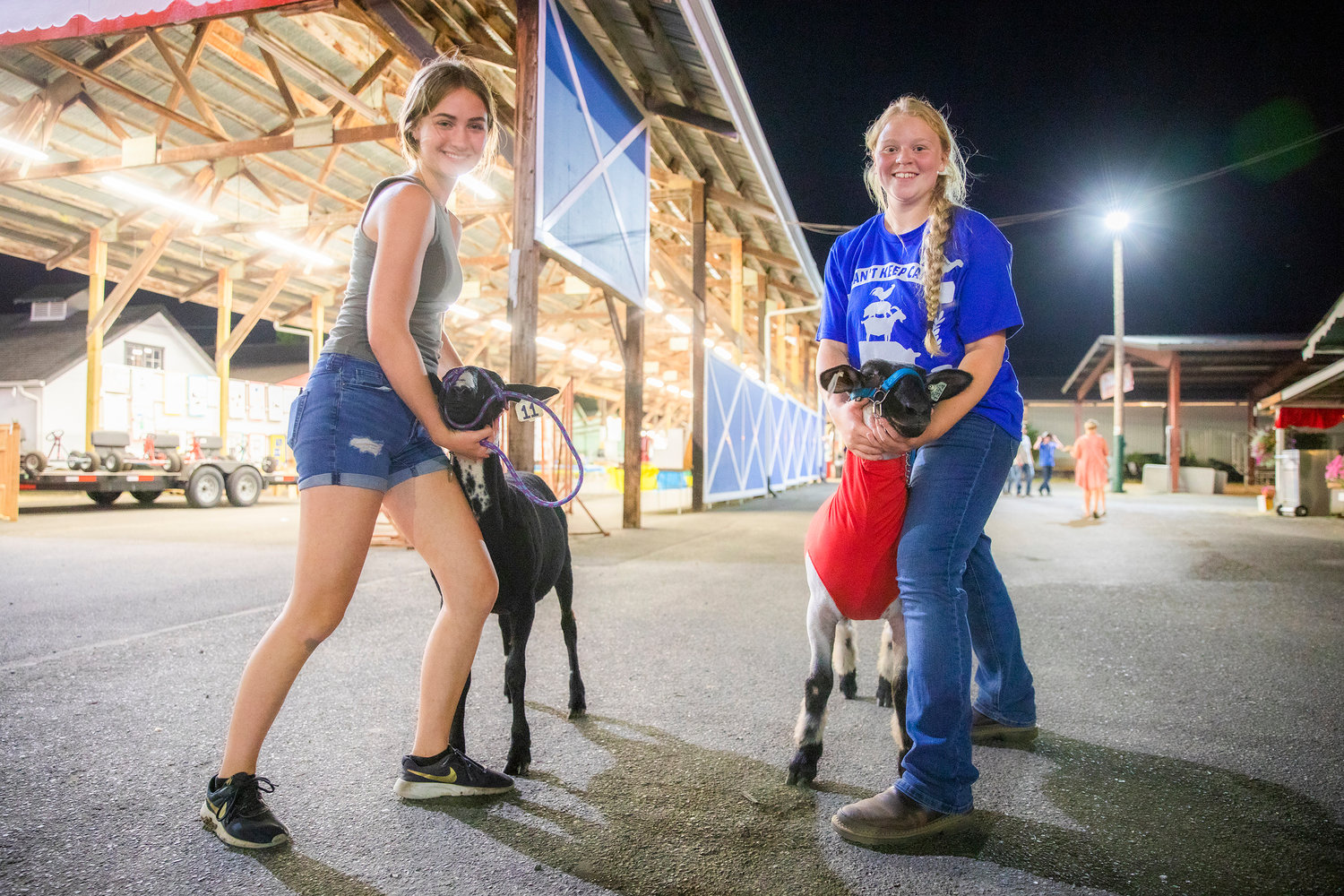 Haley Gallagher, 15, and Deseree Abrams, 15, smile and hold their sheep Juan and Shadow at the Southwest Washington Fairgrounds Tuesday night in Centralia.