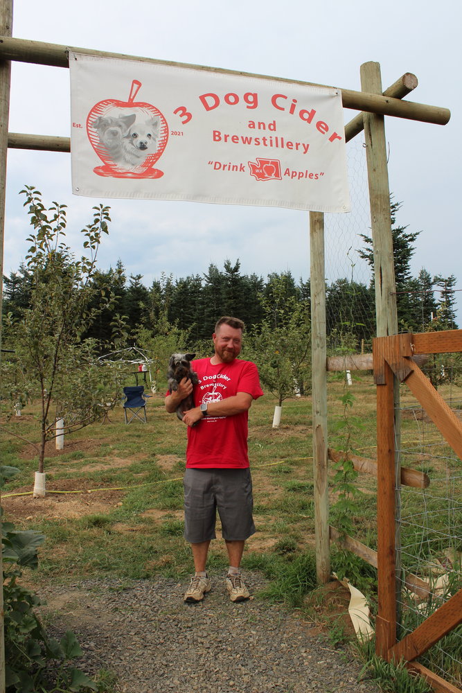 Joshua Hail, owner of 3 Dog Cider & Brewstillery in Silver Creek and resident orchard dog, Wolfie.