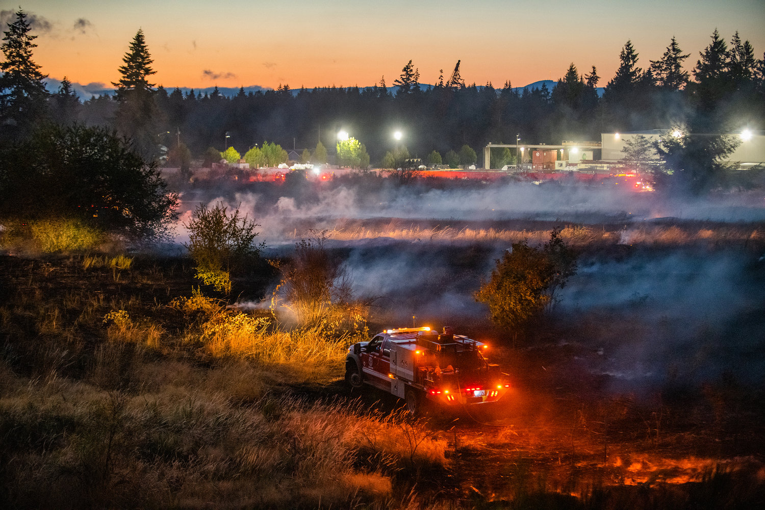 Smoke is illuminated by lights on a truck as hoses stretch across a field between Elderberry Street Southwest and Interstate 5 at milepost 88 in Grand Mound last month.
