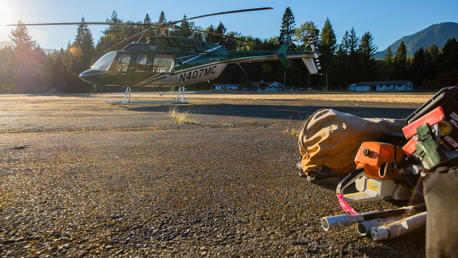 A helicopter used for reconnaissance sits on standby near picks and saws Tuesday evening at the Packwood Airport.