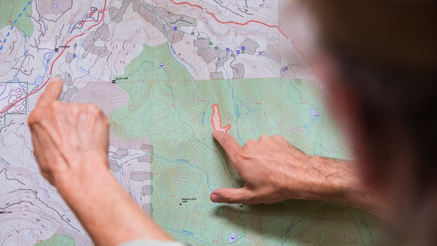 Incident Commander Dan Cottrell points out the Goat Rocks Fire on a map alongside community members Tuesday at the Packwood Community Hall.