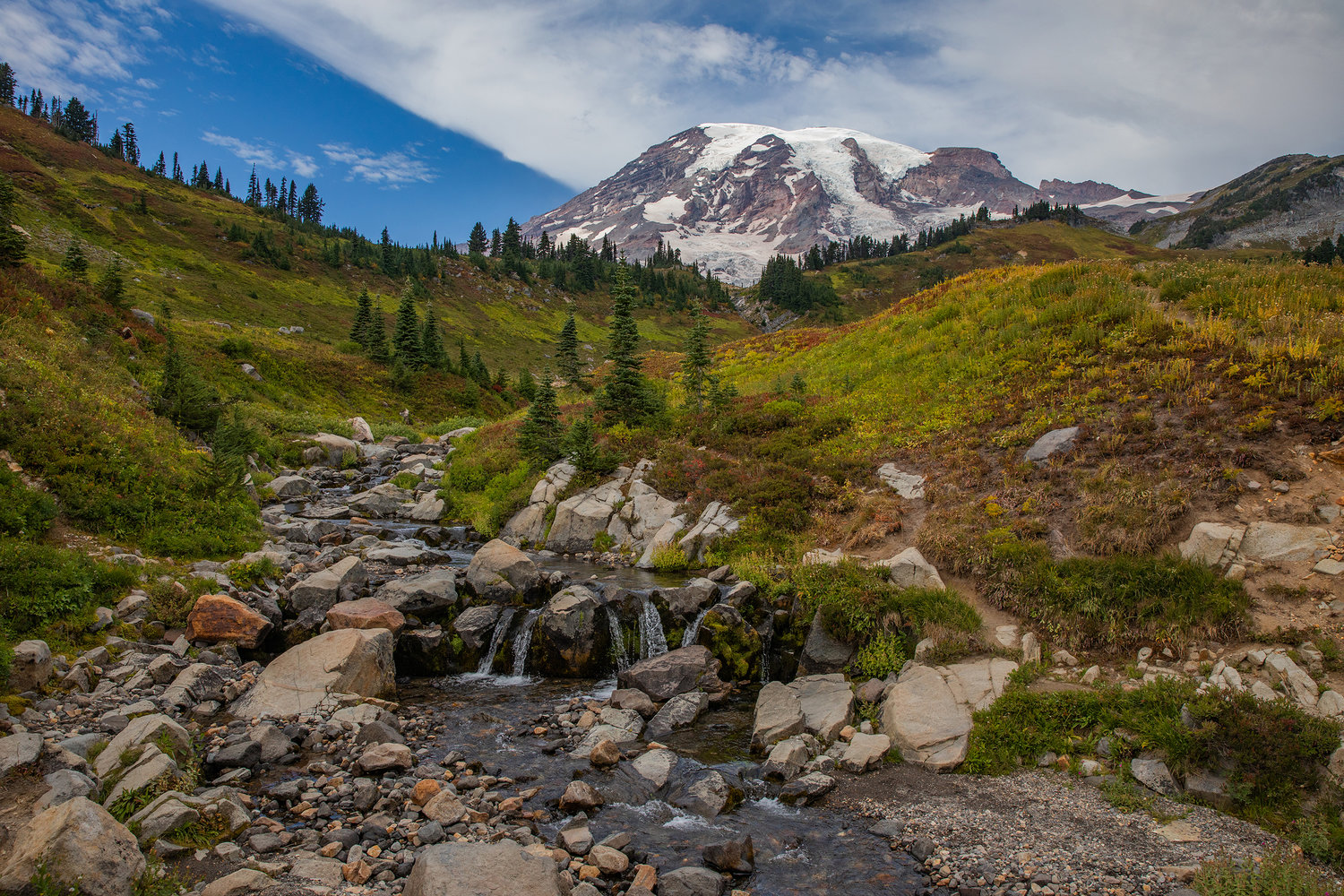 Mount Rainier sets the backdrop as water trickles down rocks near Myrtle Falls in Paradise on Wednesday.