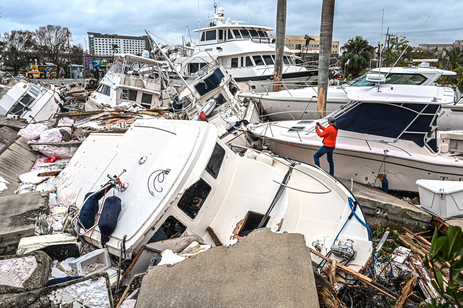 A man takes photos of boats damaged by Hurricane Ian in Fort Myers, Florida, on September 29, 2022. - Hurricane Ian left much of coastal southwest Florida in darkness early on Thursday, bringing "catastrophic" flooding that left officials readying a huge emergency response to a storm of rare intensity. The National Hurricane Center said the eye of the "extremely dangerous" hurricane made landfall just after 3:00 pm (1900 GMT) on the barrier island of Cayo Costa, west of the city of Fort Myers. (GIORGIO VIERA/AFP via Getty Images/TNS)