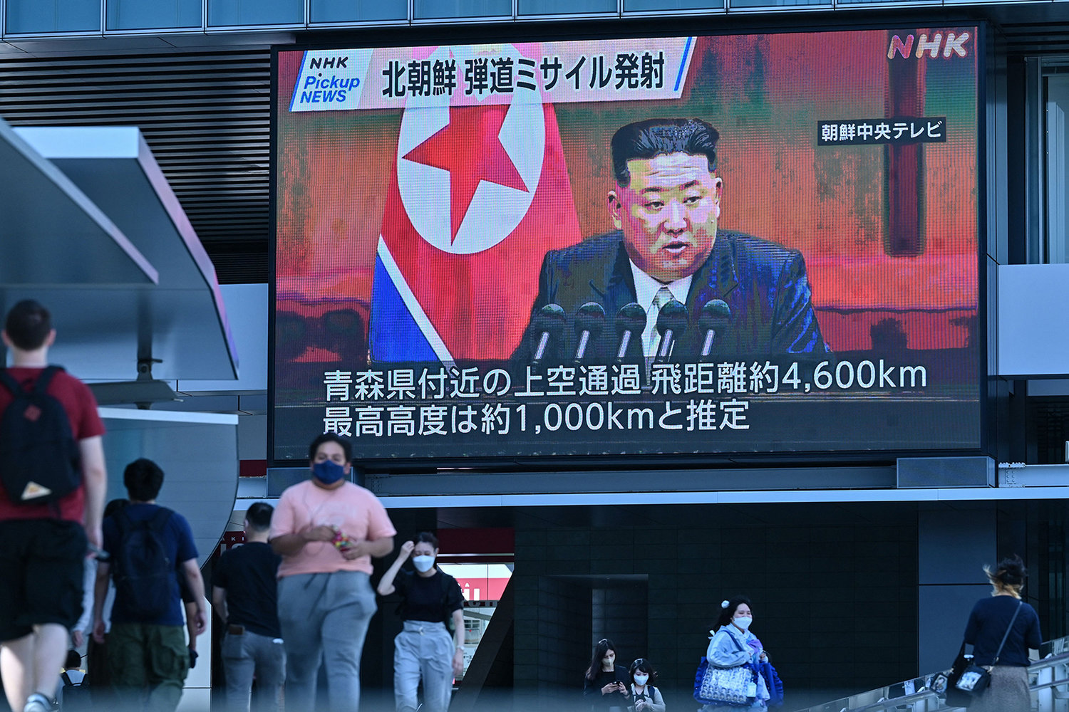 Pedestrians walk under a large video screen showing images of North Korea's leader Kim Jong Un during a news update in Tokyo on Oct. 4, 2022, after North Korea launched a missile early in the day which prompted an evacuation alert when it flew over northeastern Japan. - North Korea fired a ballistic missile over Japan for the first time in five years on Oct. 4, prompting Tokyo to activate its missile alert system and issue a rare warning for people to take shelter. (Richard A. Brooks/AFP via Getty Images/TNS)