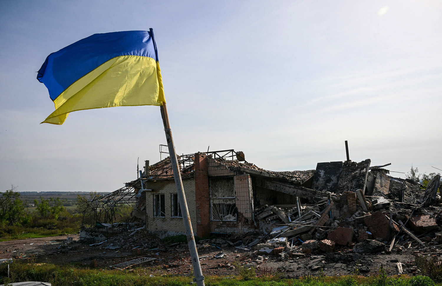 A Ukrainian national flag is displayed in front of a destroyed house near Izyum, eastern Ukraine, on Saturday, Oct. 1, 2022, amid the Russian invasion of Ukraine. (Juan Barreto/AFP/Getty Images/TNS)