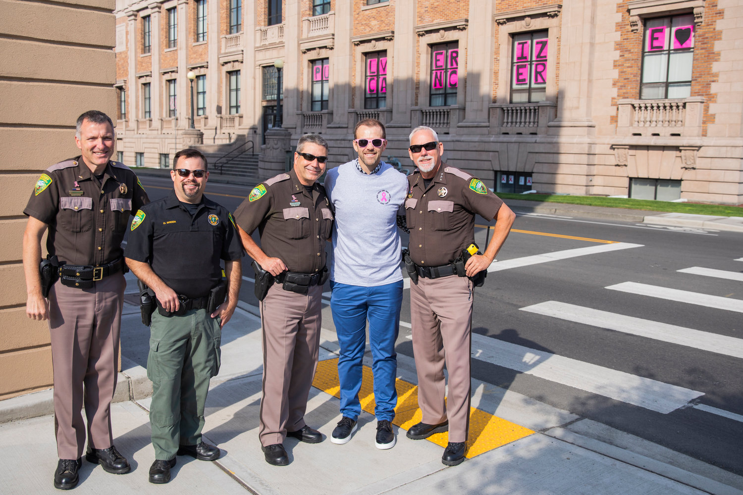 Commissioner Sean Swope smiles and poses for a photo alongside members of the Lewis County Sheriff’s Office in Chehalis on Friday during a walk for Breast Cancer Awareness Month.