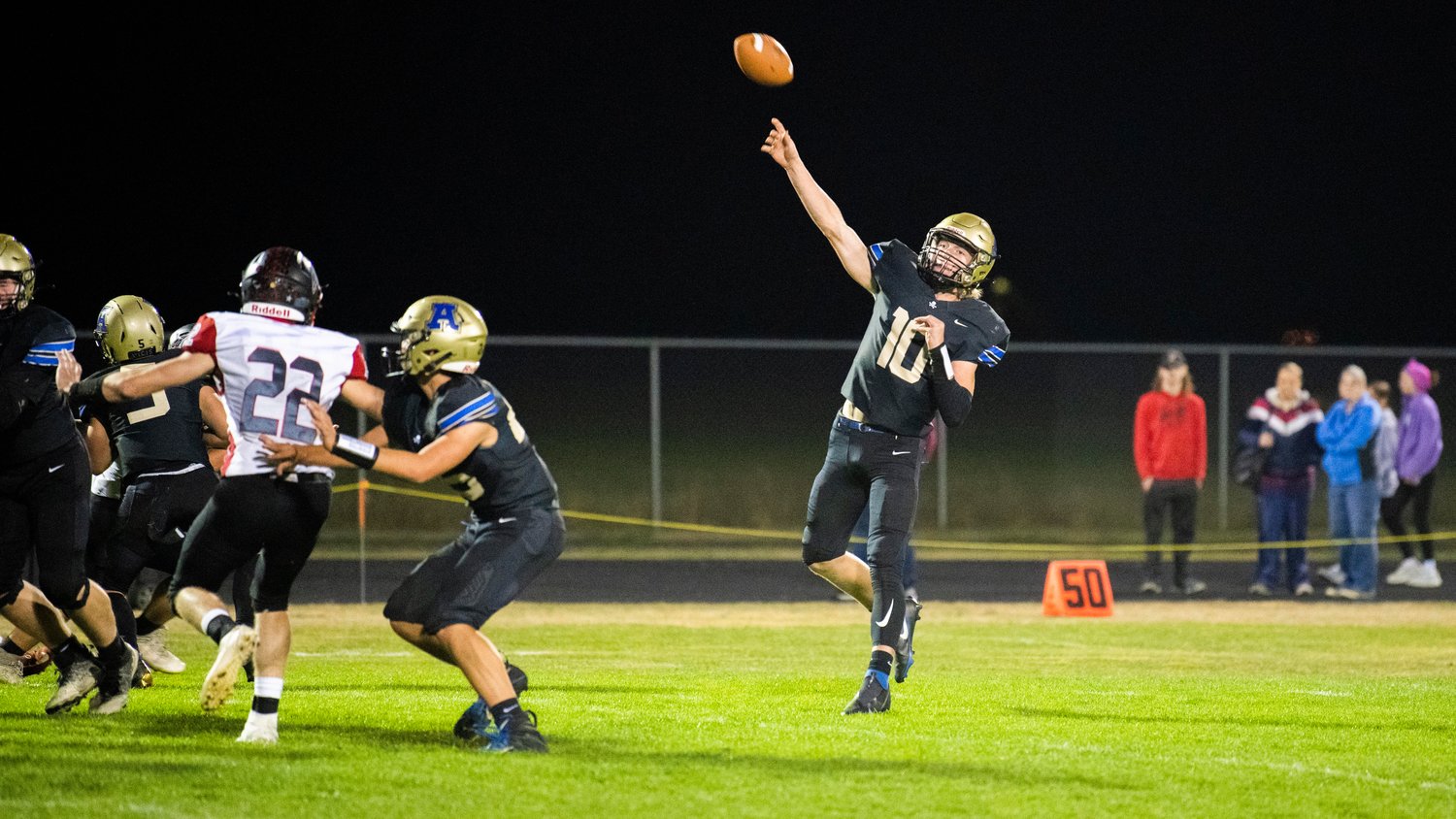 Adna junior Lane Johnson (10) launches a pass toward the end zone during a game against Toledo Friday night at Pirate Stadium as cars line up for homecoming royalty.