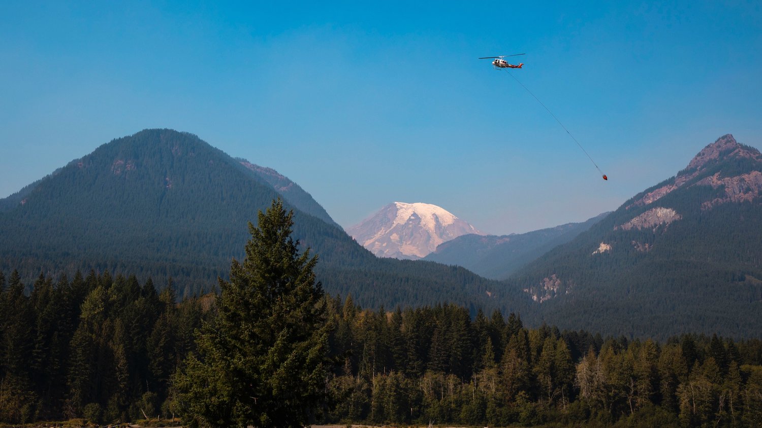 Helicopters soar over the Cowlitz River in front of Mount Rainier while responding to the Goat Rocks Fire on Sunday.