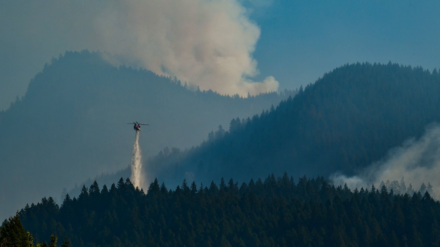 A helicopter dumps water over the Goat Rocks Fire as seen from High Valley near Packwood on Sunday.